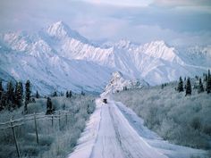 a snow covered road with mountains in the background