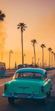 an old car is parked on the side of the road with palm trees in the background