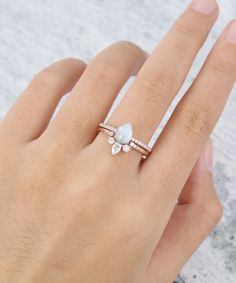 a woman's hand wearing a ring with an opalite and diamond accent