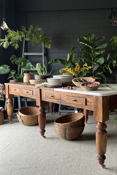 a wooden table topped with lots of plants next to pots and bowls on top of it