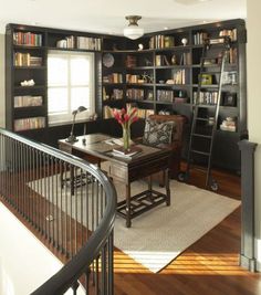 a living room filled with lots of bookshelves next to a stair case in front of a window