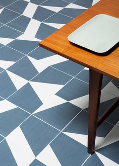 a computer mouse sitting on top of a wooden table next to a blue and white tiled floor