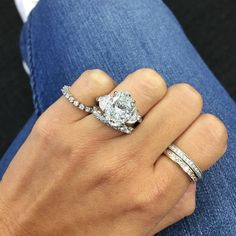 a woman's hand with two rings on her fingers and an engagement ring in the middle