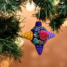 a christmas ornament hanging from a tree with decorations on it's branches