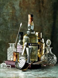 an assortment of liquor bottles sitting on top of a table next to glasses and spoons