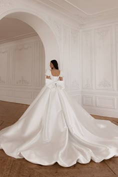 a woman in a white wedding dress standing on the floor with her back to the camera