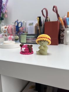 two small figurines sitting on top of a white table next to craft supplies