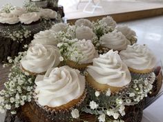 several cupcakes with white frosting and flowers are on top of a table