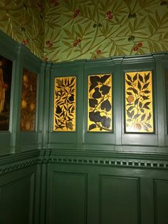 three paintings on the wall in a room with green paneling and gold leaf designs