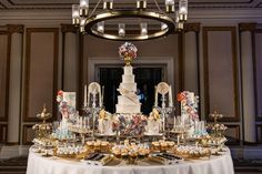 a table topped with lots of desserts next to a chandelier