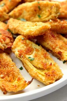 some fried food on a white plate with parsley sprinkled around the edges