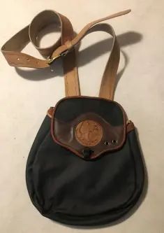 a black purse sitting on top of a white table next to a brown belt strap