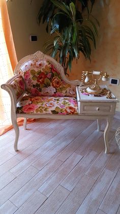 a white couch sitting on top of a wooden floor next to a potted plant