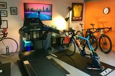 an indoor gym with bikes and treadmills in front of a flat screen tv