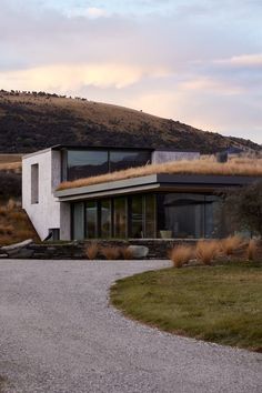 a modern house with grass on the roof and an open driveway leading up to it