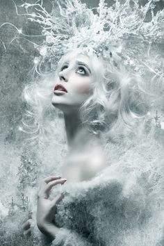 a woman with white hair and feathers on her head is surrounded by snowflakes