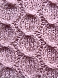 a close up view of a pink knitted blanket with circles on the front and sides