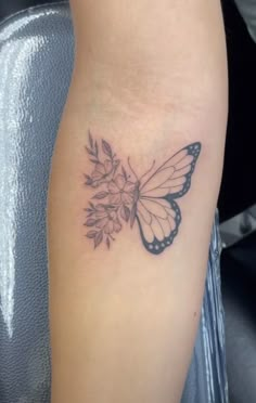 a small butterfly with flowers on it's back side tattooing the arm and shoulder