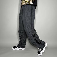 "Vintage Starter Track Pants Dark Grey Polyester Sweatpants Subtle Embroidered Logo Baggy Fit has Ankle Zippers Lined 90s Skate / Streetwear Great Condition: 9/10 Men's Size: Large My Hands in Pockets = It has Pockets No Hands in Pockets = Does Not Have Pockets Drawstring Will be Visible in Forward Pic, if not Visible it Does Not Have a Drawstring About me: I am 6' 0\" for reference I generally wear a Large (32\" inseam) I Model XS to 2XL sweatpants, I find that you can often size up or down with 95% of sweatpants and they fit the same" 90s Style Wide Leg Winter Bottoms, 90s Wide Leg Winter Bottoms, 90s Style Baggy Streetwear Pants, 90s Baggy Pants For Streetwear, 90s Style Baggy Pants For Streetwear, Relaxed Fit Casual Cargo Pants With Zip Fly, 90s Style Relaxed Fit Winter Bottoms, Casual Baggy Cargo Pants With Zip Fly, 90s Wide Leg Parachute Pants For Streetwear