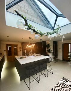 an open kitchen with a skylight above the counter and bar stools in front of it