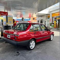 a red car parked in front of a gas station