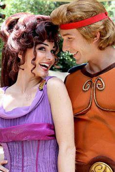 two people in costumes standing next to each other and smiling at each other's eyes