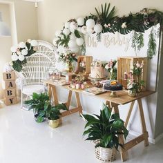 a table topped with lots of cake next to potted plants and balloons on the wall