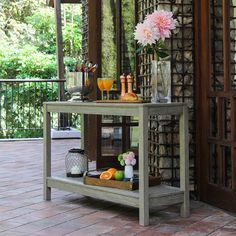 a table with drinks and flowers on it in front of an open door to a patio