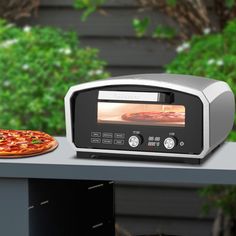 a toaster oven sitting on top of a table next to a slice of pizza