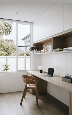 a desk with a laptop on it in front of a window that looks out onto the water