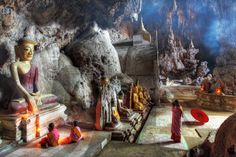 there are many statues in the cave with people sitting around and looking at something on the ground