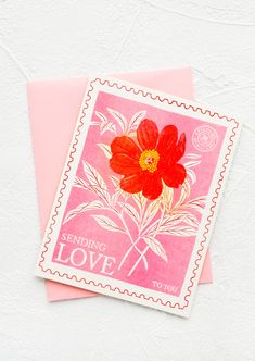 a pink envelope with a red flower on it and the words sending love written in white