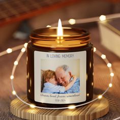 a candle that is sitting on a table with a photo in the jar next to it