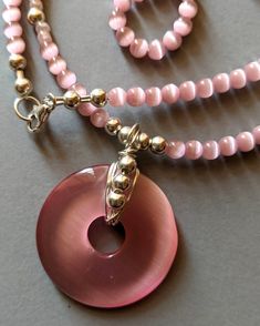 Pink cat eye beaded necklace measures 18 inches long. Beautiful pink donut shape pendant is one inch tall and wide. Necklace is made up of 4mm round cat eye beads, small pink  glass beads, and sterling silver 4mm beads. Clasp is also sterling silver. Necklace set has matching earrings.  The hook earrings are sterling silver. The pink cat eye earrings are oval shape and measure 1 and 3/4 inches long. This beautiful pink cat eye beaded necklace set is placed in delicate draw string bag and boxed for ready to gift for you. Your purchase of $35.00 or more gives you free shipping. I hope you like this necklace set as much as I have enjoyed making it for you. Pink Faceted Beads Necklace As Gift, Pink Healing Faceted Bead Necklaces, Cats Eye Beads Jewellery, Pink Spiritual Necklace With Faceted Beads, Pink Glass Necklace With Round Beads, Cat Eye Beads, Cat Eye Necklace, Pink Beaded Necklace, Pink Donut