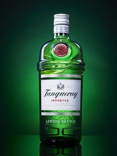 a bottle of tanqueray london dry gin sitting on a green surface with its reflection