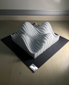 a large white sculpture sitting on top of a black piece of paper in front of a wall