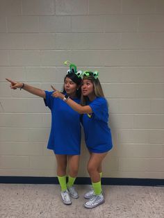 two young women dressed in blue and green posing for the camera with their arms around each other