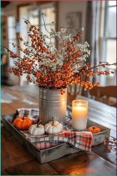 an arrangement of flowers and candles on a tray with plaid napkins in the background