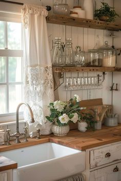 a kitchen sink sitting under a window next to a wooden shelf filled with glassware