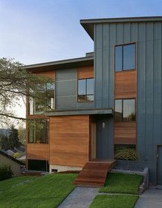 a modern house with grass and trees in the front yard