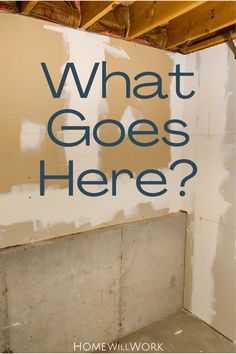 the words what goes here? written in blue on a wall with unfinished walls behind it