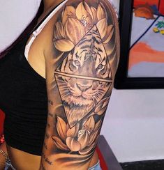 a woman's arm with a tiger and flowers tattoo on her left arm, in front of a wall