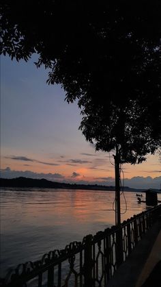 the sun is setting over the water and there are trees on the side of the lake