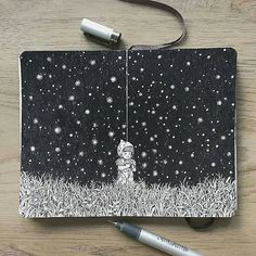 an open notebook with a drawing of a boy holding a teddy bear in the grass at night