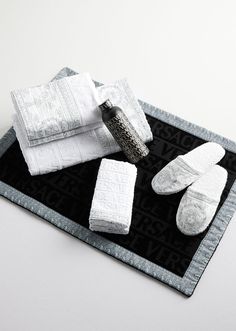 towels and slippers are laid out on a black mat with silver trimmings