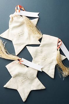 three pieces of fabric with tags attached to them on a table top, one is white and the other has orange string