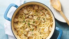 a blue pot filled with pasta and chicken on top of a white plate next to a wooden spoon