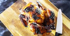 a cooked chicken sitting on top of a cutting board next to a knife