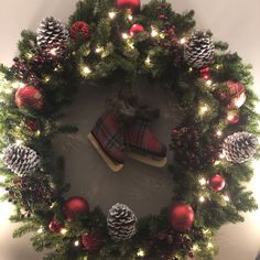 a christmas wreath with red and green ornaments on it, surrounded by pine cones and other holiday decorations