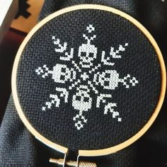 a cross - stitch pattern on a black cloth with a gold colored ring in the middle